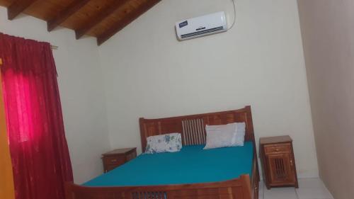 1 dormitorio con cama azul y cortina roja en Haus Independencia Guara Paraguay 
