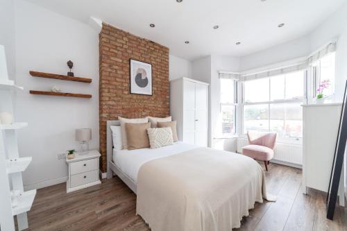 1 dormitorio con cama blanca y pared de ladrillo en The Brent Park Collection, en Londres