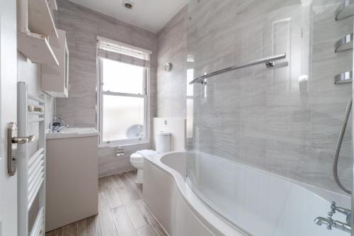 a bathroom with a tub and a toilet and a sink at The Brent Park Collection in London