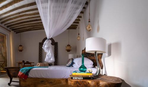 une chambre avec un lit et une table avec une lampe dans l'établissement Infinity Beach Boutique Hotel & SPA, à Matemwe