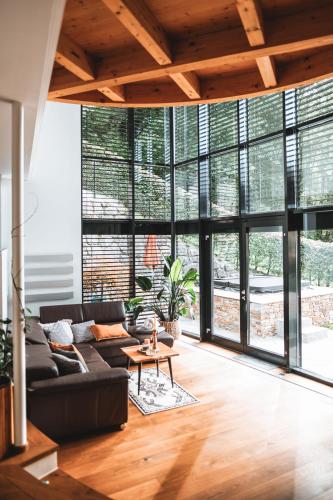 a living room with a black couch and large windows at Villa Bergl.21 in Brixlegg