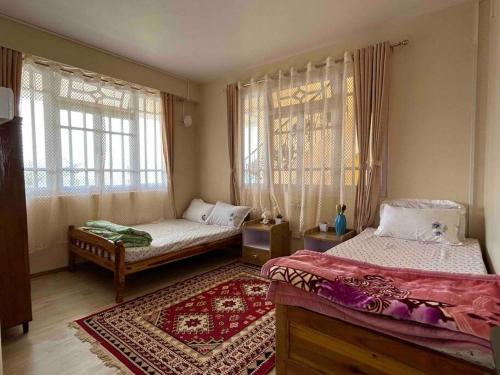 a bedroom with two beds and a rug at Ejam House, with a tea garden view in Darjeeling