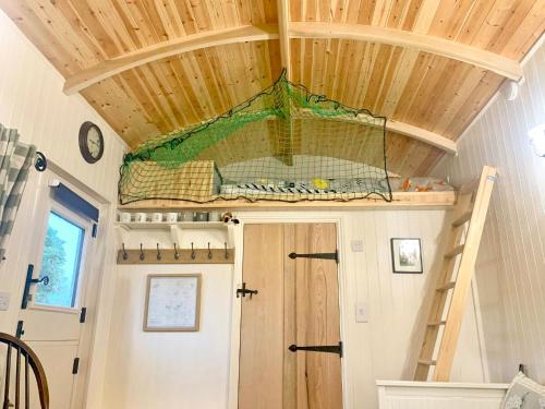 a tiny house with a ceiling with a net at Beautiful Shepherd's Hut - Lois Weedon in Weston