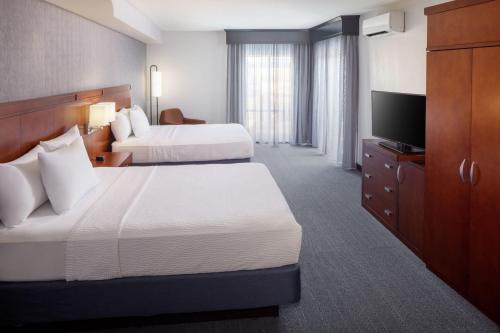 a hotel room with two beds and a flat screen tv at Courtyard by Marriott Charleston Downtown/Civic Center in Charleston