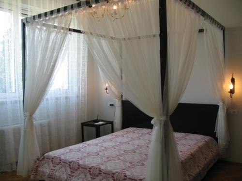 1 dormitorio con cama con dosel y cortinas blancas en Villa Raisa, en Opatija