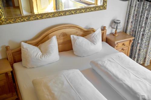 a bedroom with a bed with two pillows and a mirror at Alt Montafon Hotel Appartements by Pferd auf Wolke in Gaschurn