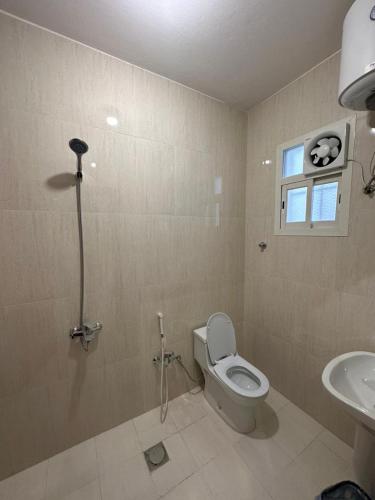 ein Badezimmer mit Toilette und Waschbecken und einem Fenster in der Unterkunft بودل روز للشقق المخدومة in Abha