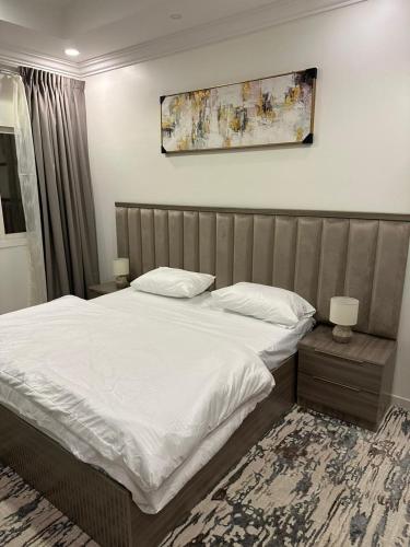 ein Schlafzimmer mit einem großen Bett mit weißer Bettwäsche in der Unterkunft بودل روز للشقق المخدومة in Abha
