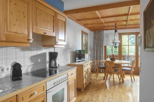 a kitchen with wooden cabinets and a table with chairs at Alt Montafon Hotel Appartements by Pferd auf Wolke in Gaschurn