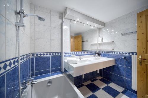 a blue and white bathroom with a sink and a tub at Alt Montafon Hotel Appartements by Pferd auf Wolke in Gaschurn