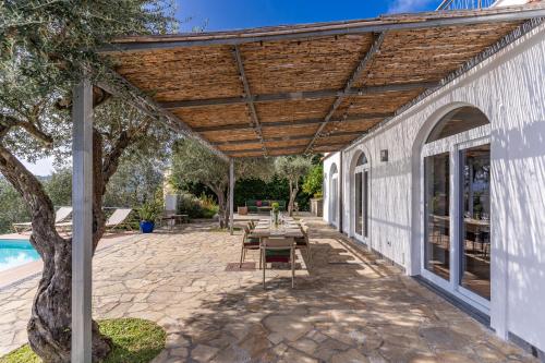 a patio with a wooden pergola next to a pool at Villa Chez Piè with Heated Infinity Pool in SantʼAgata sui Due Golfi