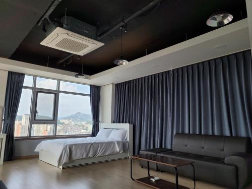 een slaapkamer met een bed, een bank en een raam bij YD Residence in Seoul