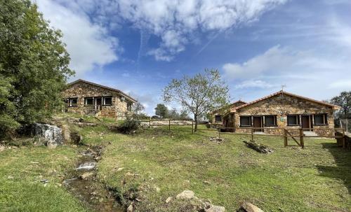 een stenen huis in een veld naast een gebouw bij Apartamentos Los Pocillos in Gargantilla del Lozoya