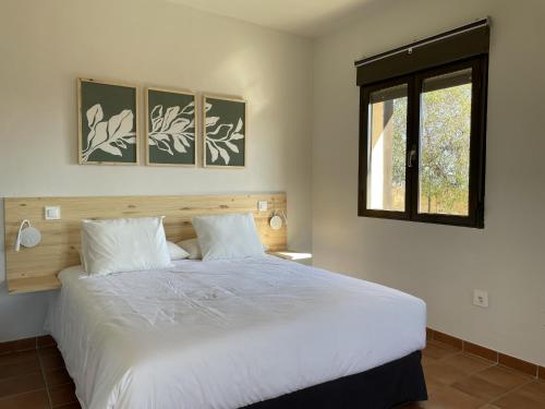 a bedroom with a large white bed with a window at Apartamentos Los Pocillos in Gargantilla del Lozoya