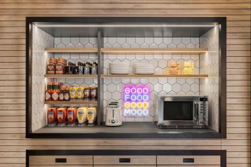 a kitchen with a microwave and a shelf with food at Moxy Vienna City East in Vienna