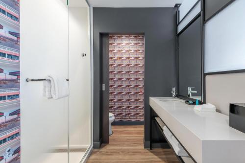 a bathroom with two sinks and a brick wall at Aloft Denver North Westminster in Westminster