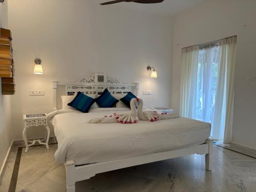 a bedroom with a large white bed with decorations on it at Oceanic - Luxury Boutique Hotel in Palolem