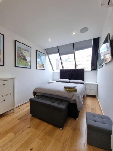 a bedroom with a bed and a ottoman at Deluxe Townhouse Zone 1 Brick Lane in London