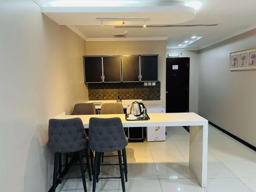 a kitchen with a white table and two stools at اصالة الشروق للشقق المخدومه in Al Khobar