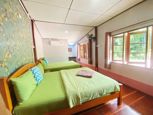 a room with two green beds and a window at Ban Choengkao in Ko Kood