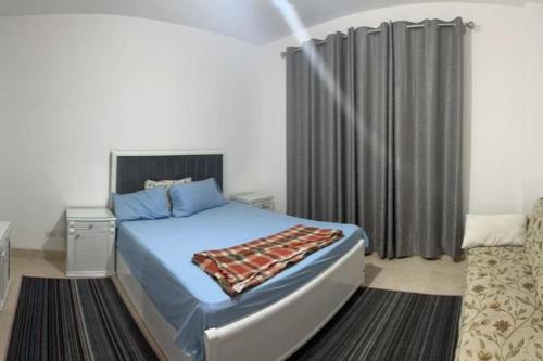 um quarto com uma cama azul e uma cortina preta em Appartment in New Cairo Madinaty em New cairo