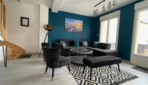 sala de estar con sofá negro y paredes azules en Chambre Songe dans maison au calme, en Compiègne