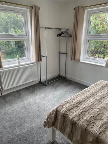 a bedroom with a bed and two windows at Lovely Two Bedroom House in Central Kidlington in Kidlington
