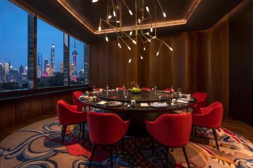 a dining room with a table and red chairs at W Shanghai - The Bund in Shanghai