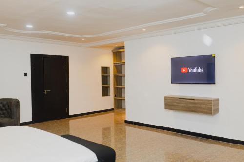 a bedroom with a tv on a white wall at Ovic Hotel in Benin City