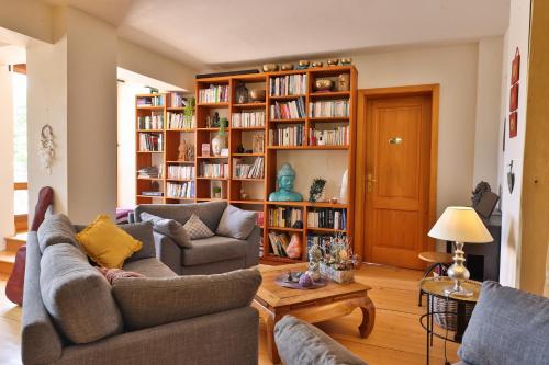 a living room with two couches and a book shelf at Le Manoir des Sens - Forêt de Bergheim in Thannenkirch