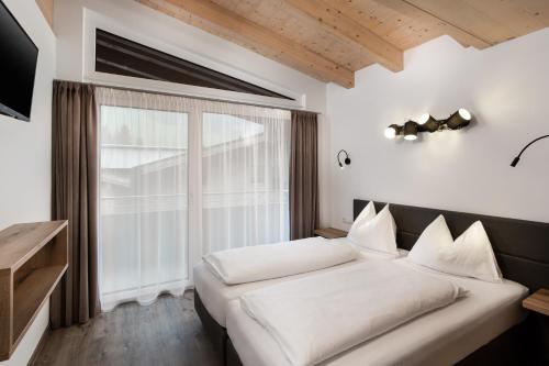 um quarto com uma cama e uma grande janela em Appartement Christina em Saalbach Hinterglemm