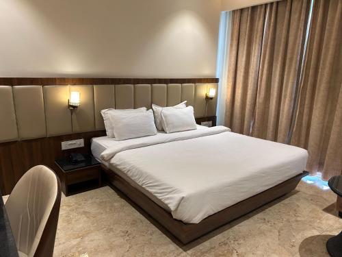 1 dormitorio con 1 cama grande con sábanas y almohadas blancas en The Imperial Prime Clarks inn Suites, Bhilwara, en Bhīlwāra