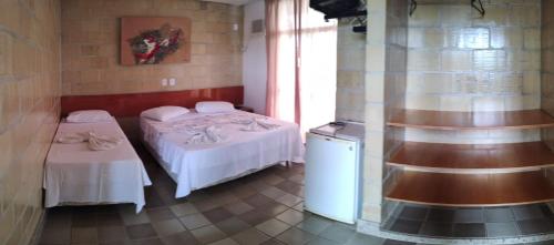 a room with two beds and a refrigerator in it at Vila Real in São Mateus