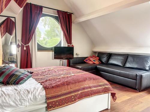 een slaapkamer met een bed en een bank bij Suite de luxe avec espace salon et balnéo à la campagne in Opprebais