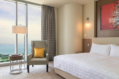 a bedroom with a bed and a chair and a window at Le Meridien City Center Doha in Doha