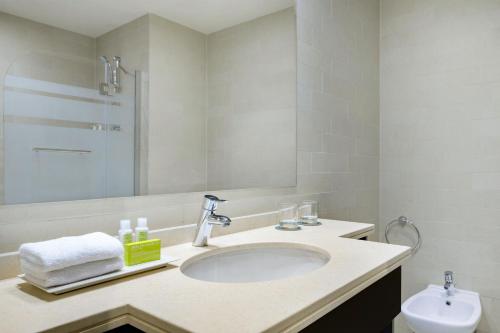 a white bathroom with a sink and a toilet at Le Meridien City Center Doha in Doha