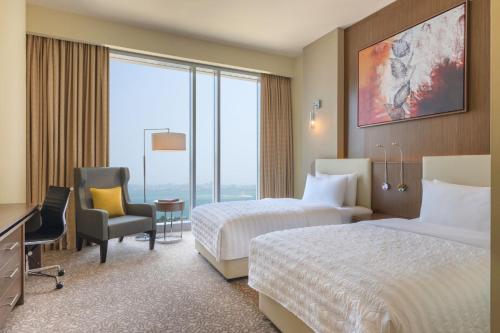 a hotel room with two beds and a desk at Le Meridien City Center Doha in Doha