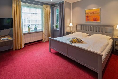 a bedroom with a large bed and a television at Hotel am Elisabethufer in Jever