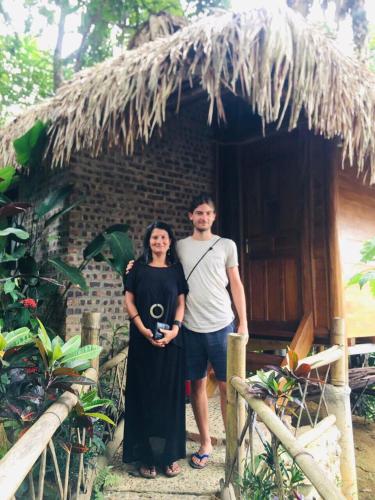 a man and a woman standing in front of a hut at Pu Luong Ecostay in Lũng Tiềm