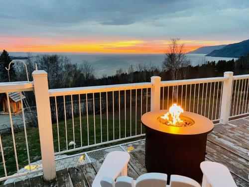 a table and chairs on a deck with a sunset at Auberge Cap aux Corbeaux in Baie-Saint-Paul