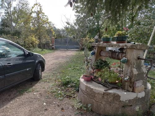 a car parked next to a stone structure with potted plants at Chambre à la campagne in Saint-Aubin-en-Charollais