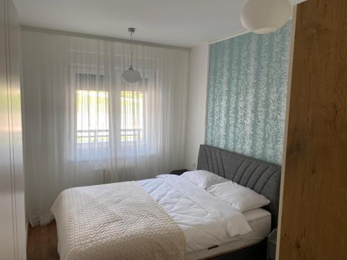 1 cama en un dormitorio con ventana y 1 sofá cama en Zeus apartman, en Hiseti