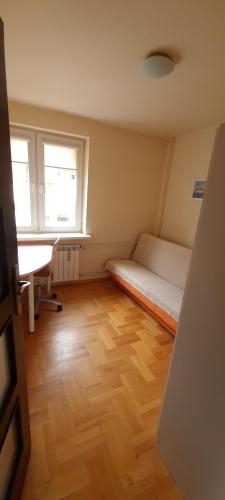 a room with a bed and a desk and two windows at Apartament Czarny Potok in Krynica Zdrój