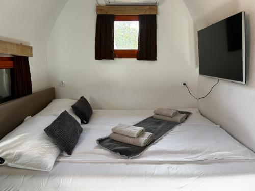 een wit bed met kussens en een flatscreen-tv bij Glamping PEC - All Inclusive light in Selnica ob Dravi