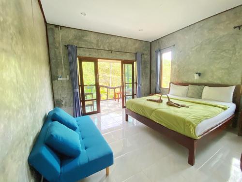 a bedroom with a bed and a blue chair at Ban Choengkao in Ko Kood