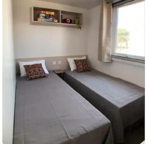 two beds in a room with a window at Mobil home Canet Roussillon 4 étoiles le Mar Estang 8 pers in Canet-en-Roussillon