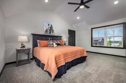 a bedroom with a bed with an orange comforter and a window at Serenity Shores Resort - Luxury Lakefront Lodge - Pools and Many Free Amenities in Kimberling City