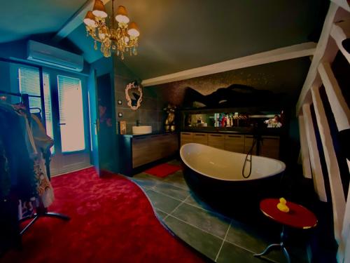 une salle de bain avec une grande baignoire et un tapis rouge dans l'établissement Love-Room Chic&Glam', à Saint-Vincent-de-Paul