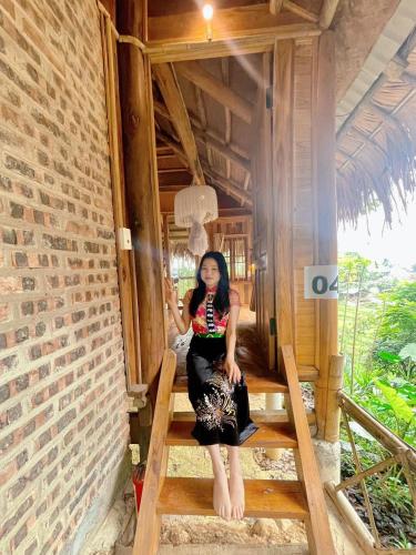 a woman sitting on a stairs in a house at Pu Luong Ecostay in Lũng Tiềm