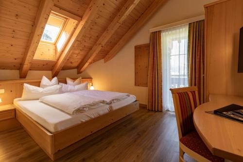 a bedroom with a bed and a desk and a window at Alpenhotel Erika in Ischgl